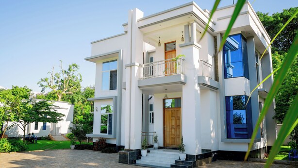 Une maison moderne à deux étages, dotée d’un balcon, d’une porte d’entrée et d’une allée pavée.