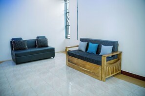 A room with two sofas, one dark grey and one wooden, with cushions. - Heim villa (Moshi)