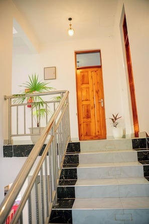 A staircase with a wooden door at the top, a potted plant, and a metal railing. - Heim villa (Moshi)