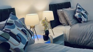 A hotel room with two beds, a nightstand with lamps, and abstract wall art. - Specious & Cosy 3 Bedroom House in Colchester/pet-friendly with free parking (Colchester)