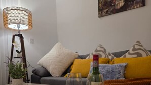 A cozy living room with a round coffee table, a floor lamp, a painting on the wall, and a sofa with cushions. - Specious & Cosy 3 Bedroom House in Colchester/pet-friendly with free parking (Colchester)