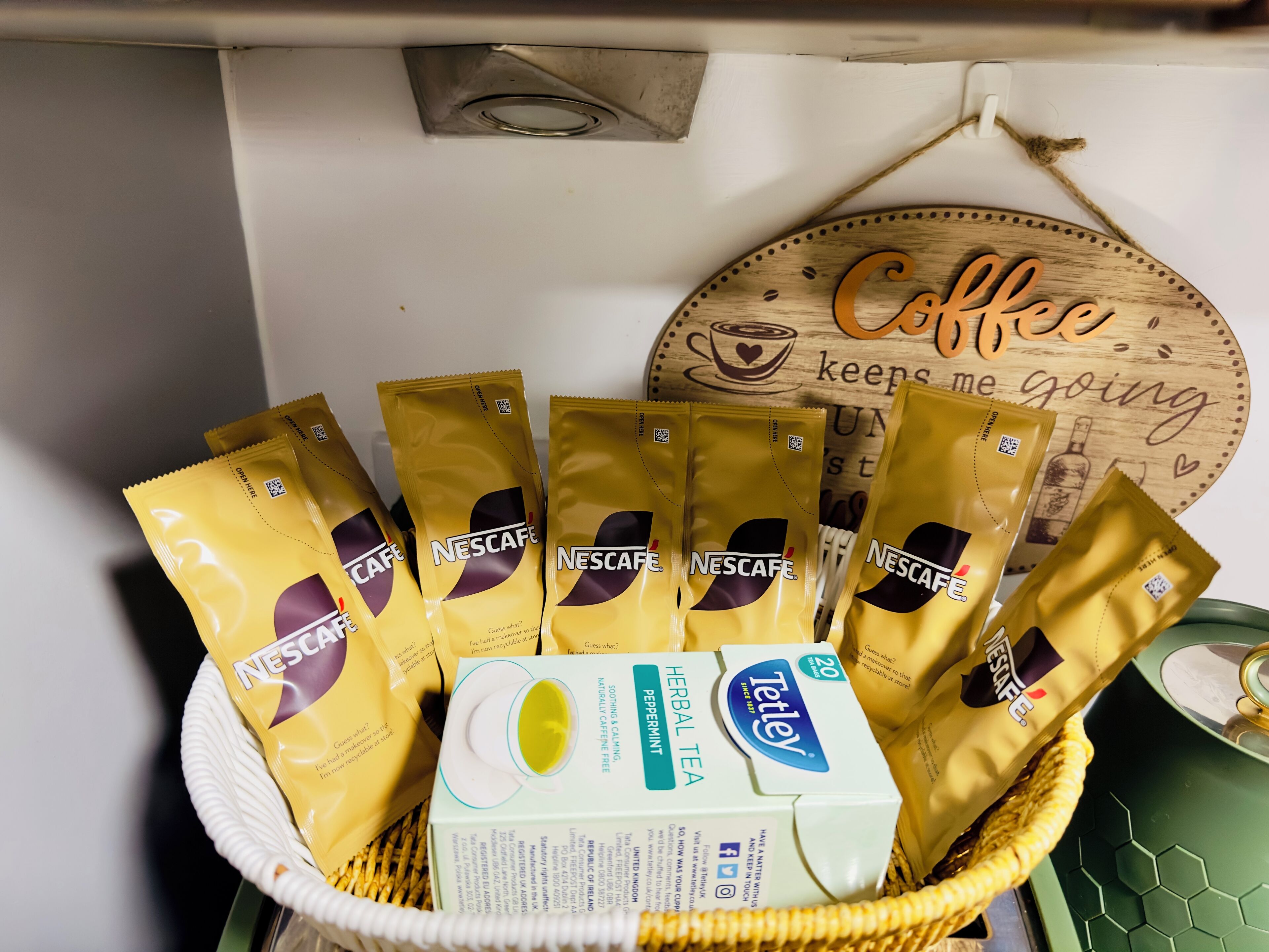 Un panier contenant plusieurs paquets de café Nescafé et une boîte de thé Tetley.