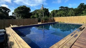 A rectangular swimming pool with a wooden deck surrounding it. - Pousada Terras Verdes (Fernando de Noronha)