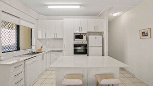 A modern kitchen with white cabinetry, a central island, a microwave, oven, and refrigerator. - Lindomare Unit 1, 11 Orvieto Tce, Kings Beach (Kings Beach)