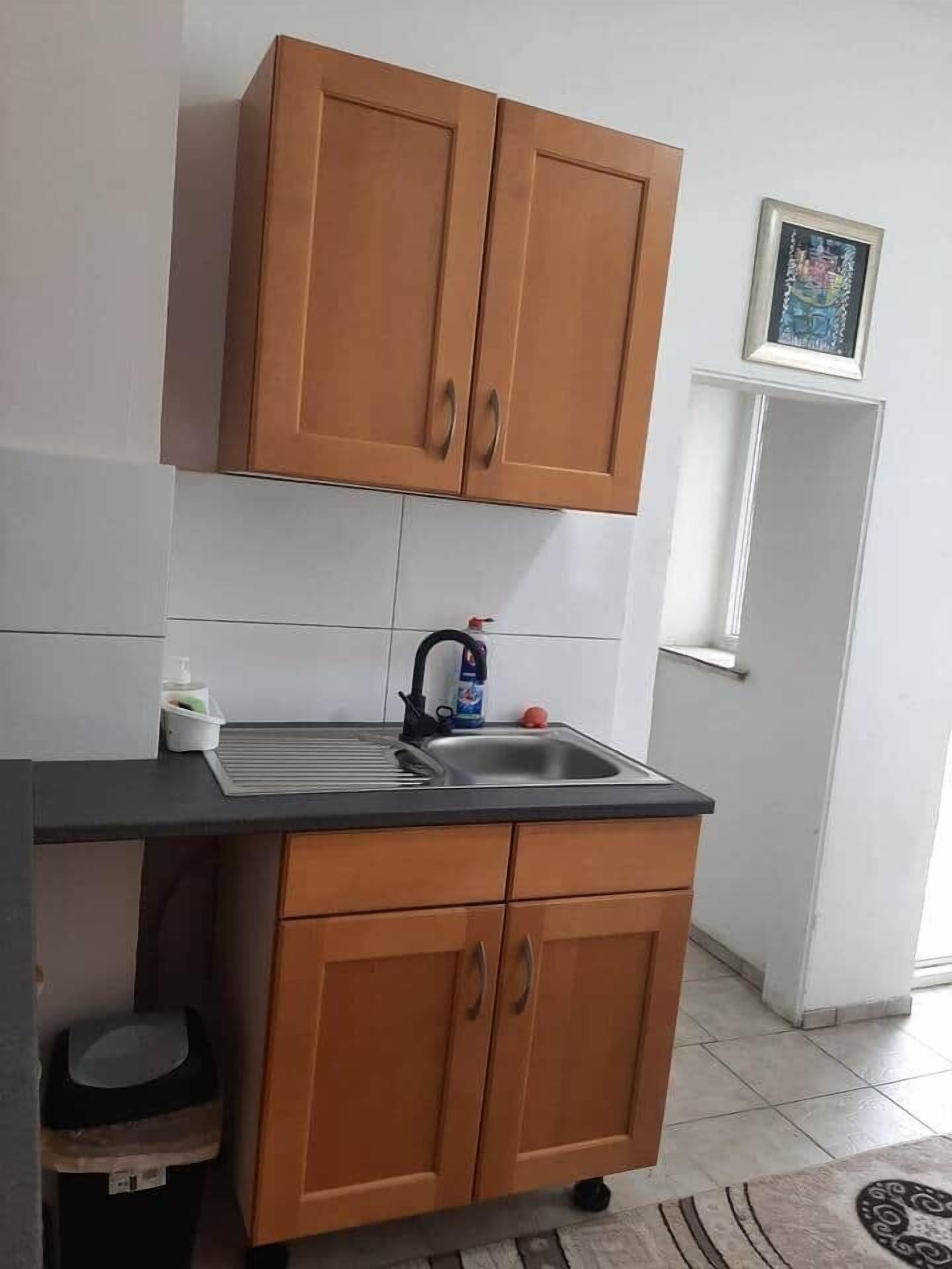 Una cocina pequeña con armarios de madera, un lavamanos y una encimera.