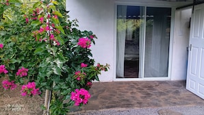 A white door with a glass panel, a stone-paved entrance, and a small wooden shelf with a pot. - Cabin with beautiful view of Coatepeque Lake, Santa Ana to relax, AC, hot water+ (Santa Ana)