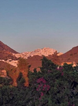 Un paisaje montañoso con una estructura en la cima, rodeado de árboles y arbustos.