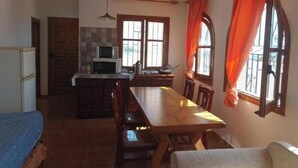 Cocina compacta con comedor, microondas y mesa con sillas.
