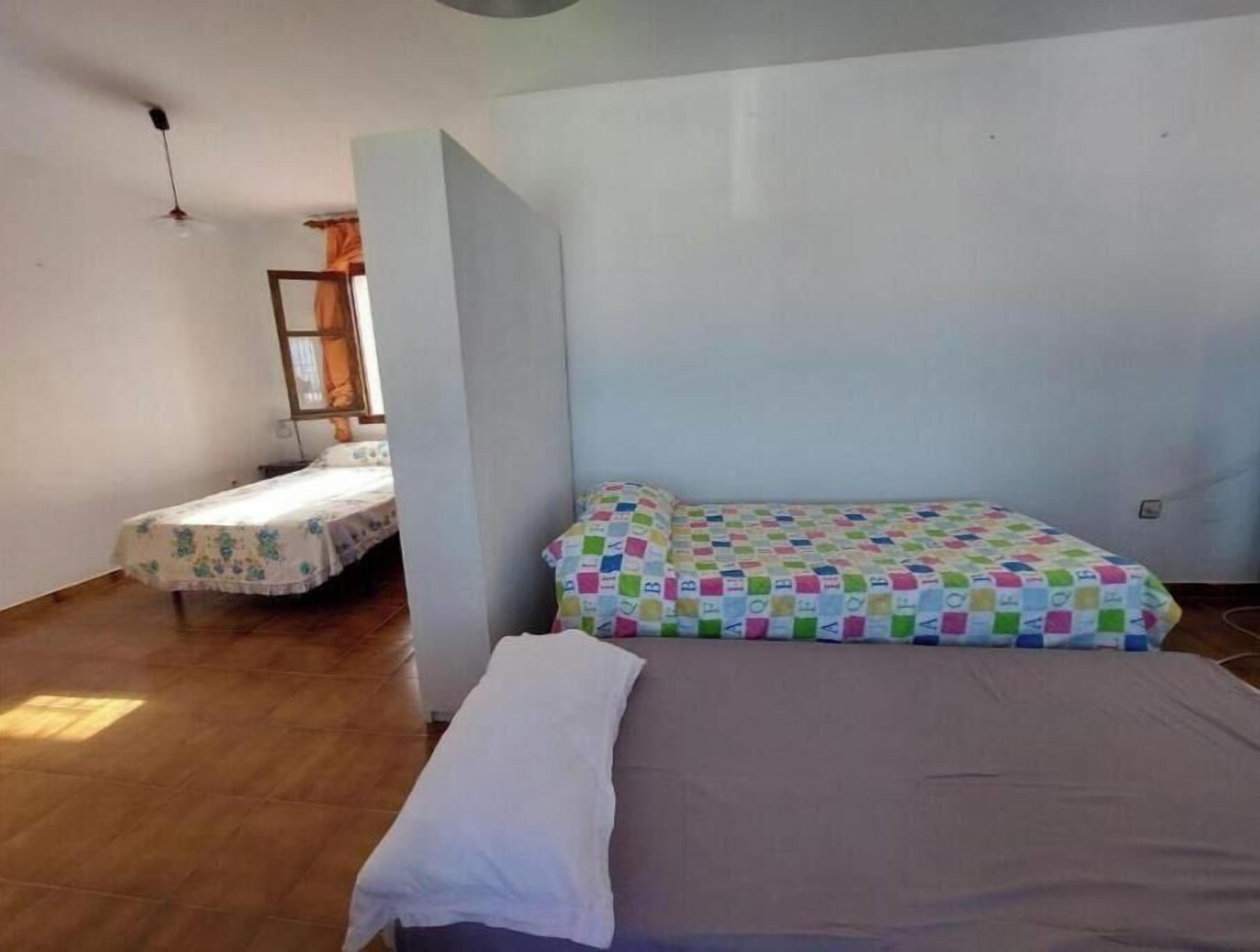 Ein Zimmer mit zwei Betten, eines mit einer bunten Steppdecke und das andere mit einem Blumenmuster.