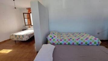 Ein Zimmer mit zwei Betten, eines mit einer bunten Steppdecke und das andere mit einem Blumenmuster.