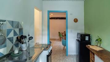 Una cocina con estufa a gas, un refrigerador negro y un comedor con mesa y sillas.