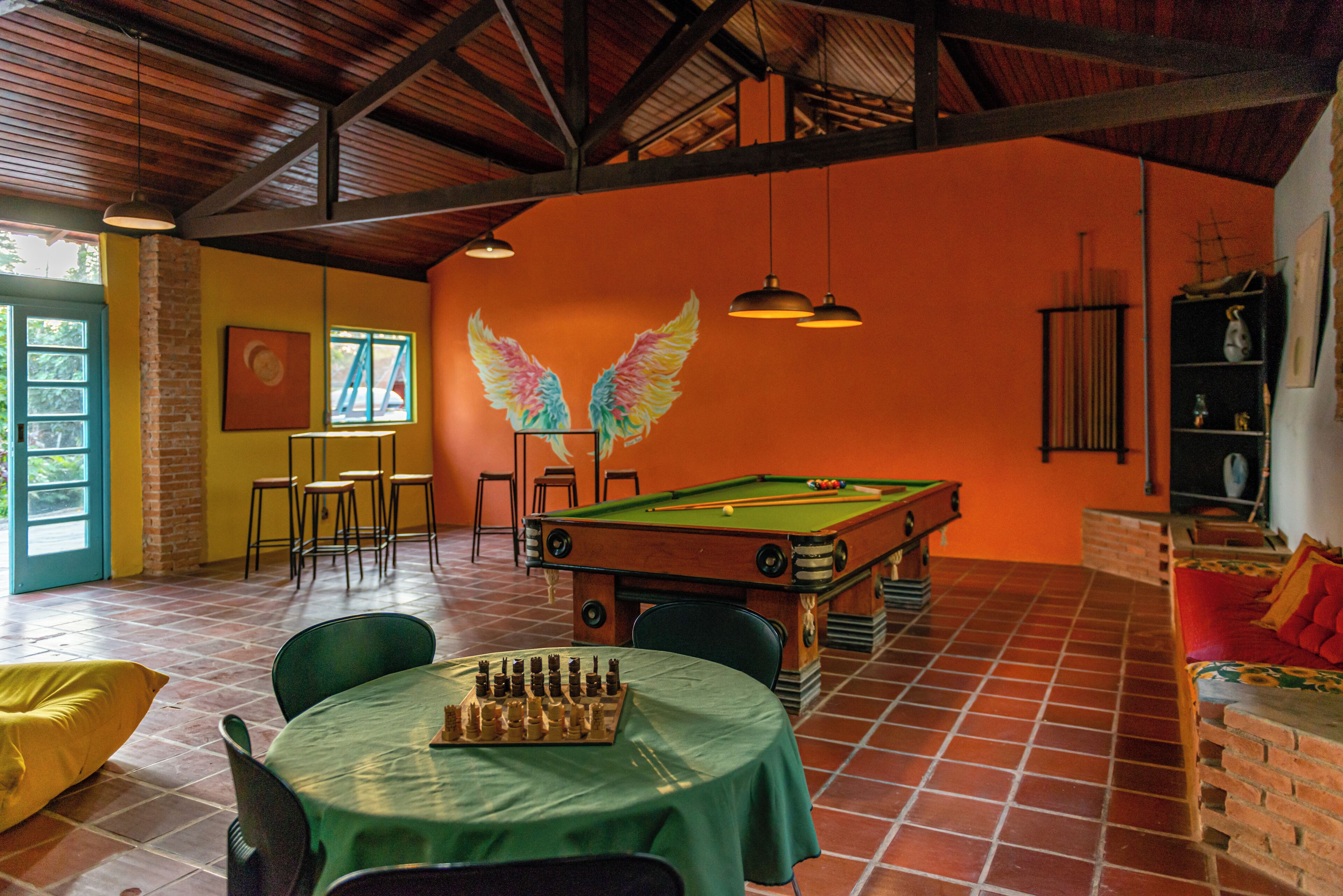 Una sala de billar con mesa de pool, sillas y mantel verde.