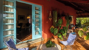 Une pièce avec un mur rouge, une porte bleue et un sol carrelé. On y trouve deux chaises et une table sur laquelle est posée une plante.
