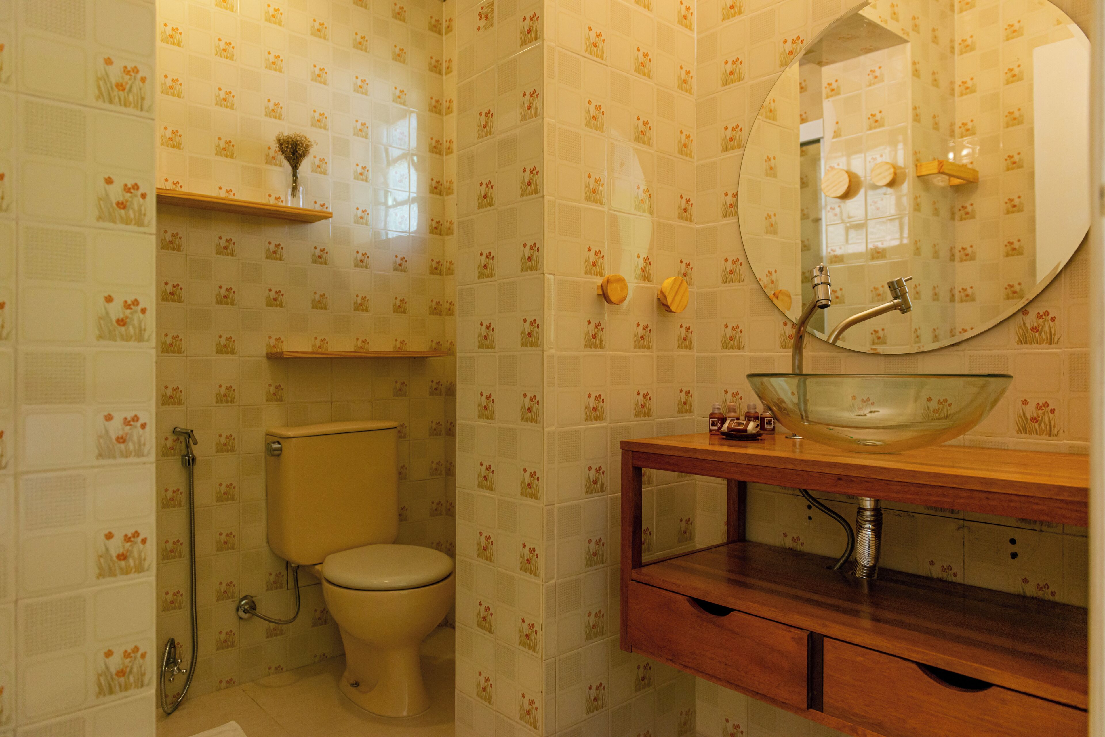 Un baño con inodoro, ducha, lavabo de vidrio y espejo.