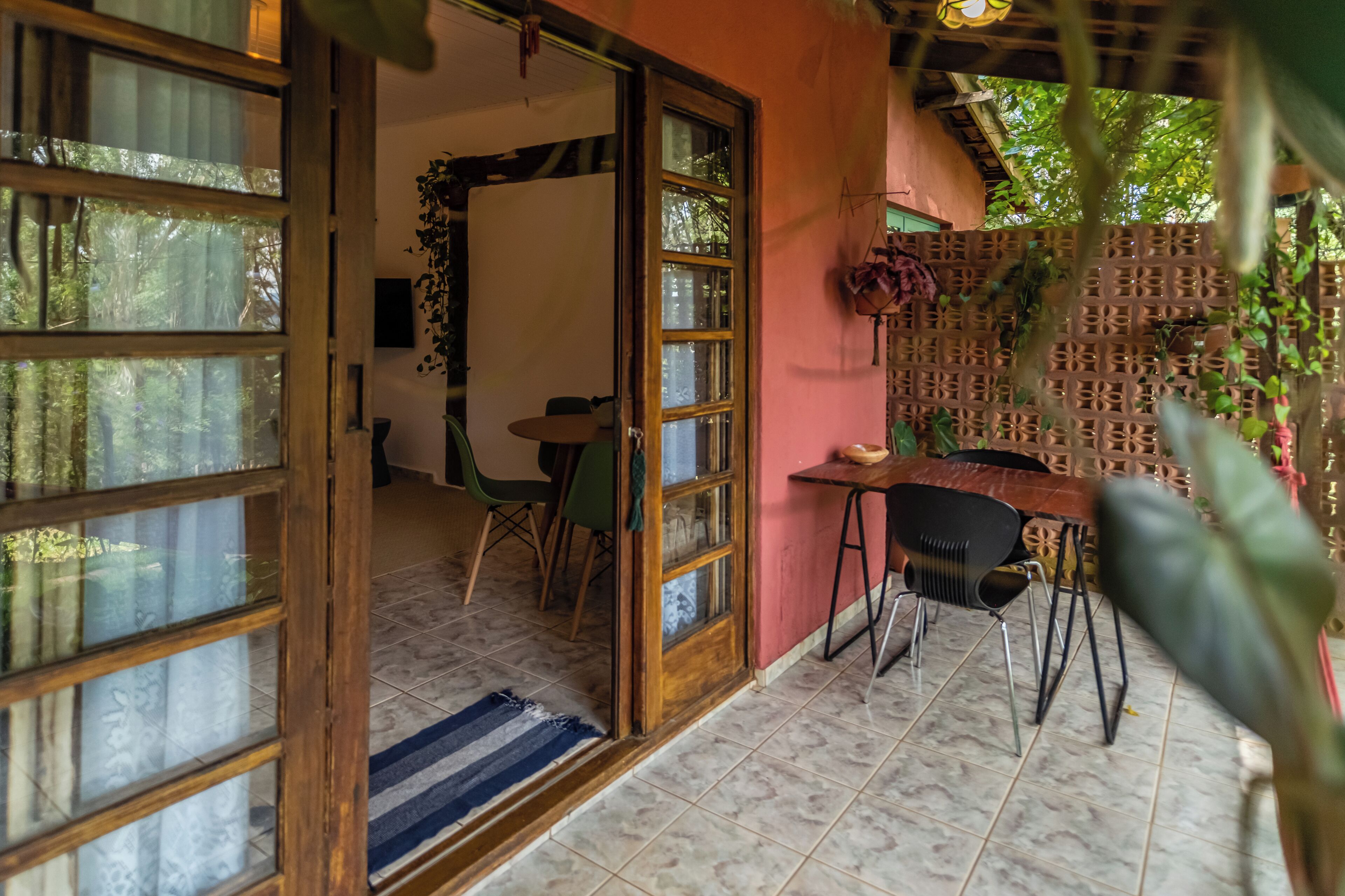 Une pièce dotée d’une porte en bois qui donne sur un coin repas, avec une table et des chaises, une petite table sur laquelle est posée une plante, et un panneau décoratif mural.