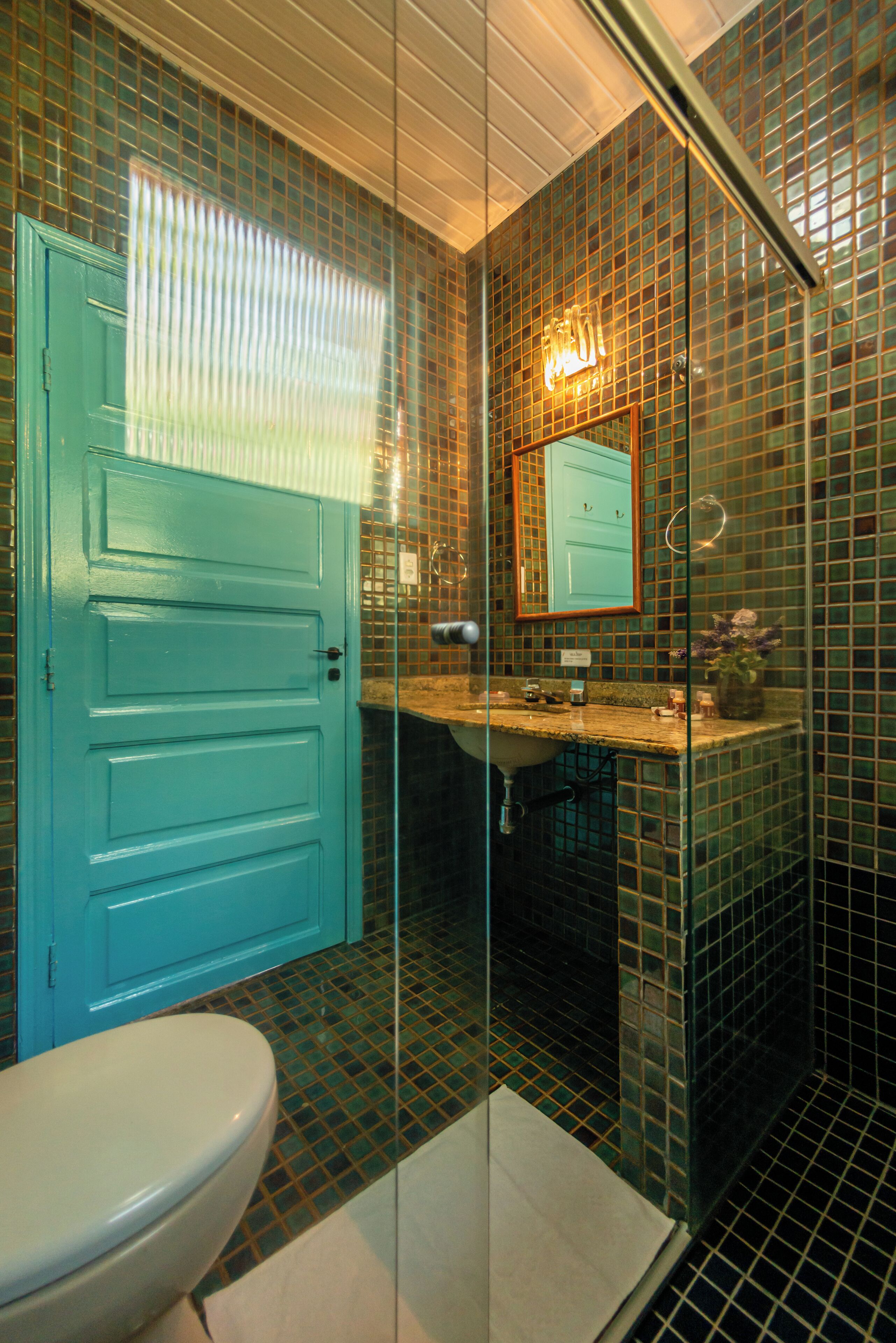 Un baño con puerta azul, lavabo y espejo.