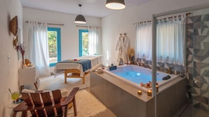 Une salle de spa équipée d’une baignoire, d’une table de massage et de chaises en bois.