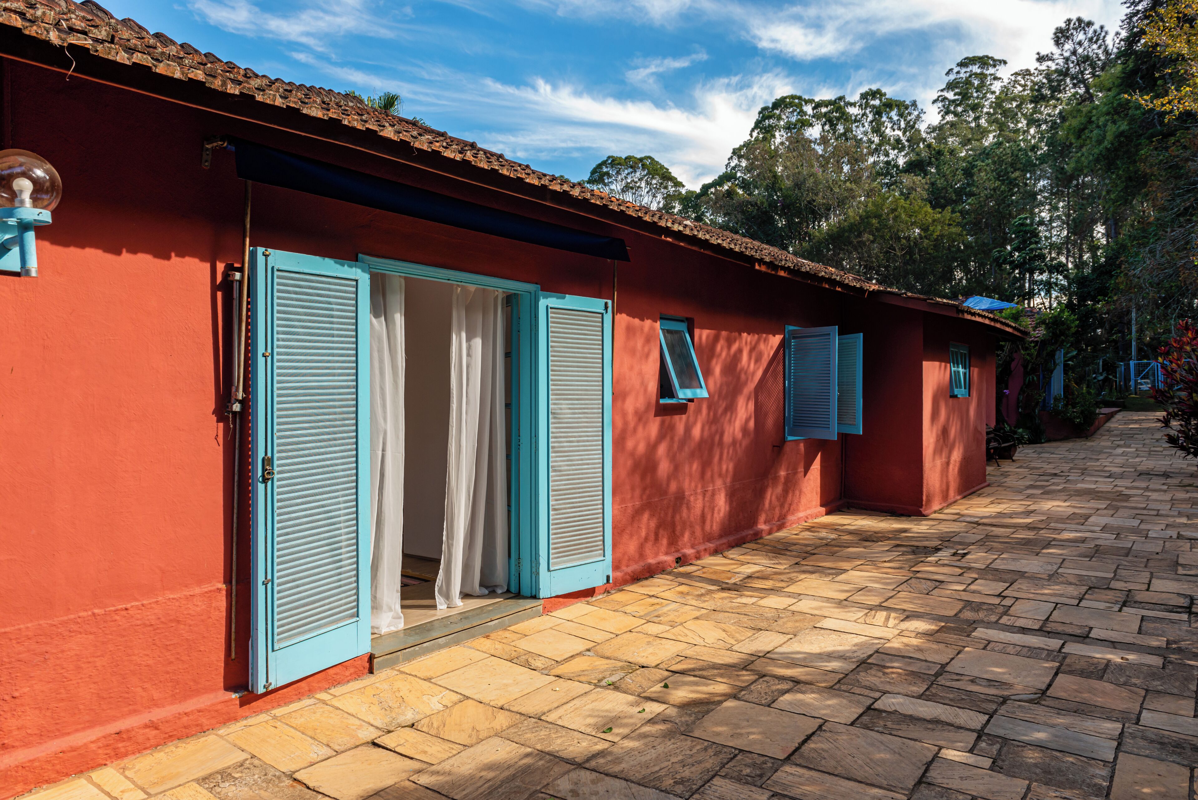 A red building with blue shutters and a tiled walkway.