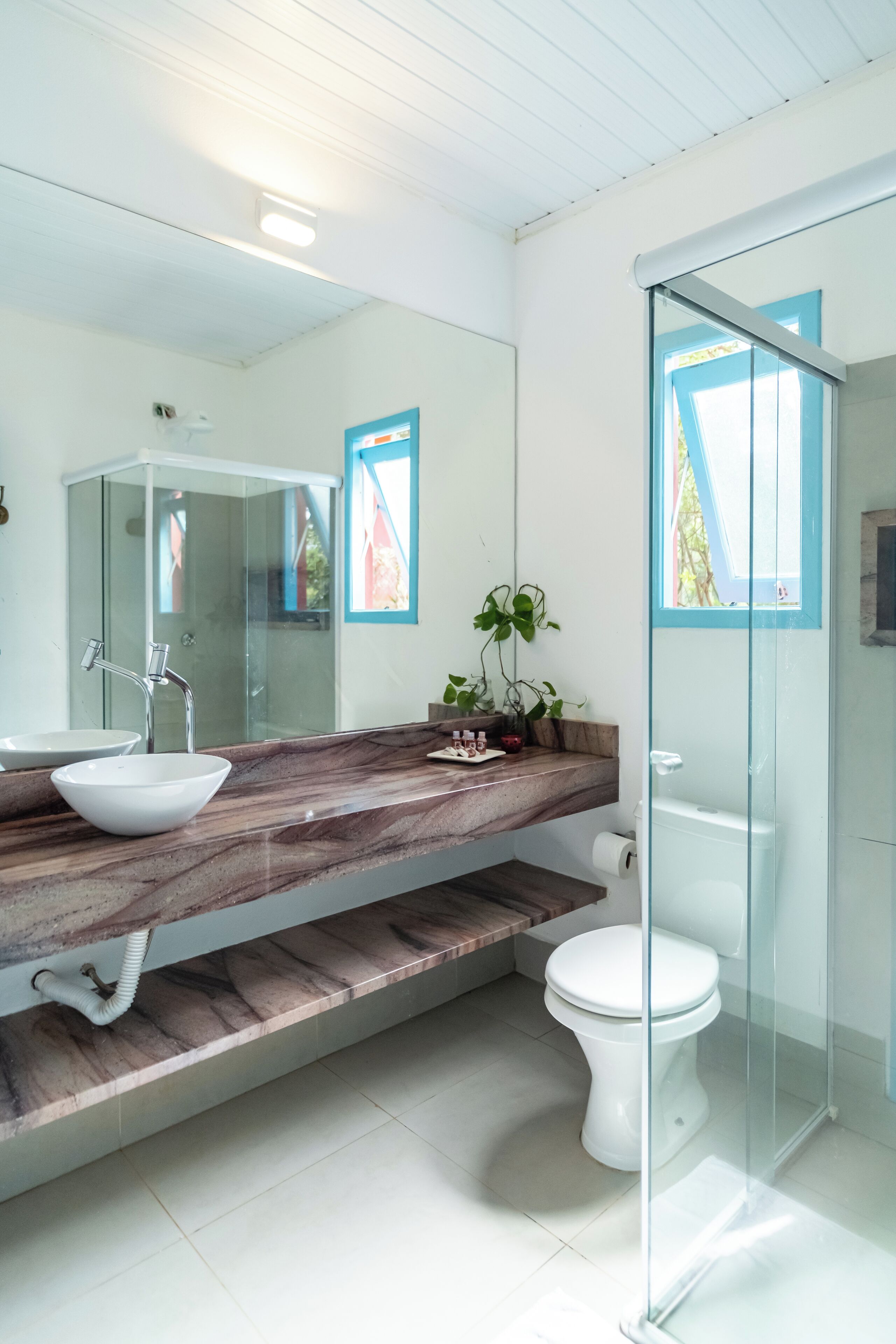 Un baño moderno con cabina de ducha de vidrio, un lavamanos blanco y encimera de mármol.