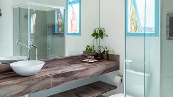 Un baño moderno con cabina de ducha de vidrio, un lavamanos blanco y encimera de mármol.