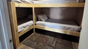 Una habitación pequeña con literas, una alfombra estampada y paredes de madera.