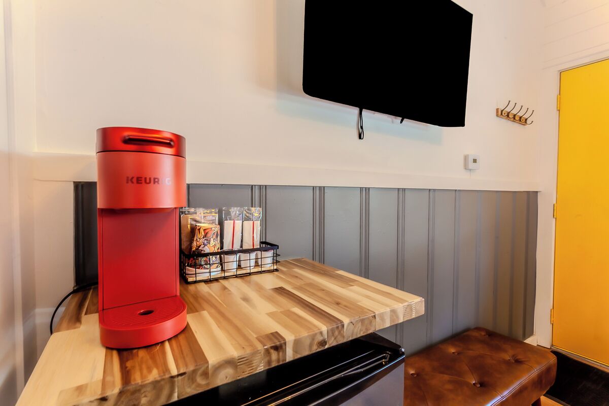 Una cafetera roja Keurig sobre una encimera de madera, con un electrodoméstico negro debajo.