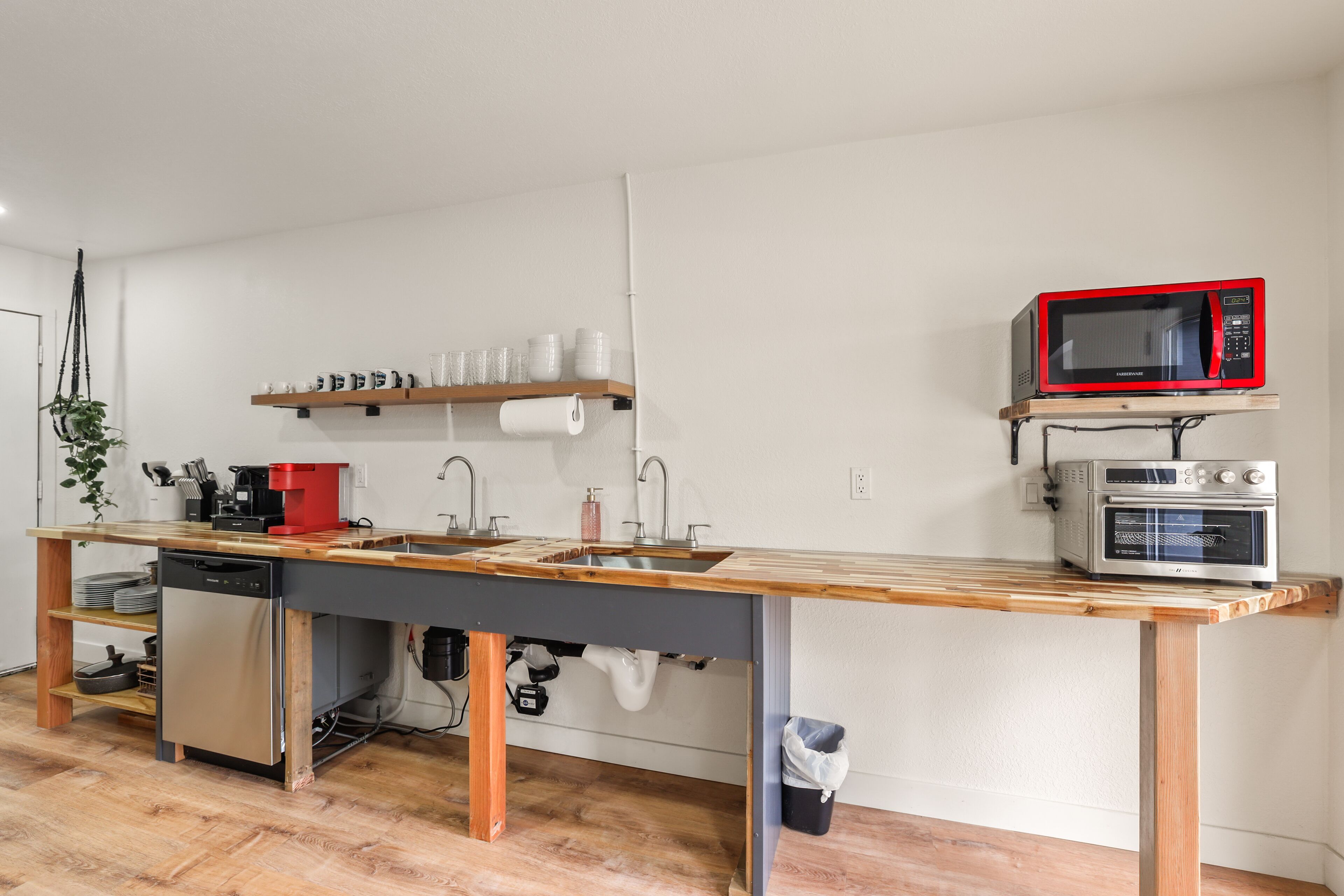 A compact kitchen with a wooden countertop, a built-in sink, a microwave, and a coffee machine.