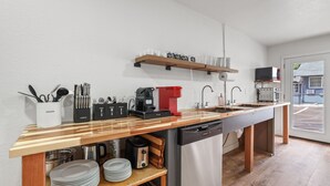 Eine moderne Küche mit einer Holzarbeitsplatte, einem Geschirrspüler, einer Kaffeemaschine und einer Mikrowelle.