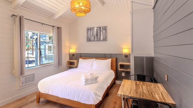 Una camera da letto con un letto di legno, un tavolo e una lampada a sospensione.