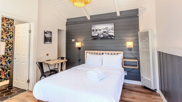 A bedroom with a bed, bedside table, lamp, and a wall-mounted air conditioner. - Tahoe Mountain Inn #20 (SOUTH LAKE TAHOE)