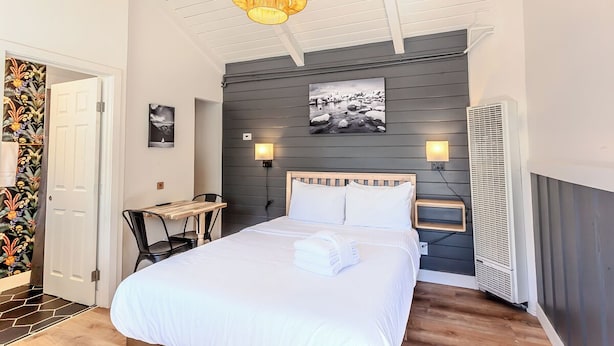Een slaapkamer met een bed, nachtkastje, lamp en een wandairconditioner.