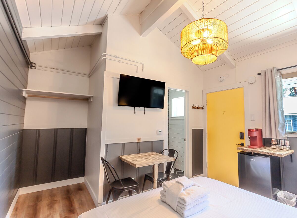 Een moderne hotelkamer met een bed, een bureau, een stoel, een televisie en een koffiezetapparaat.