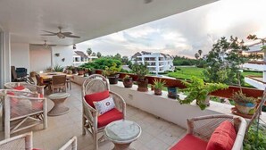 A balcony with wicker furniture, ceiling fans, and potted plants. - Penthouse Unit, Great for Families (Cozumel)