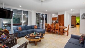 A spacious living area with a blue sofa, wooden dining table, and chairs. - Penthouse Unit, Great for Families (Cozumel)