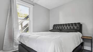 Un dormitorio con una cama grande, una ventana con cortinas y vistas a una escalera exterior.