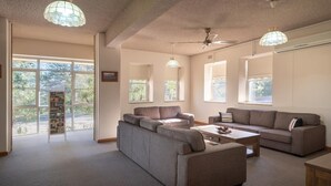 A spacious living room with a grey sofa set, a coffee table, and a bookshelf by the window.