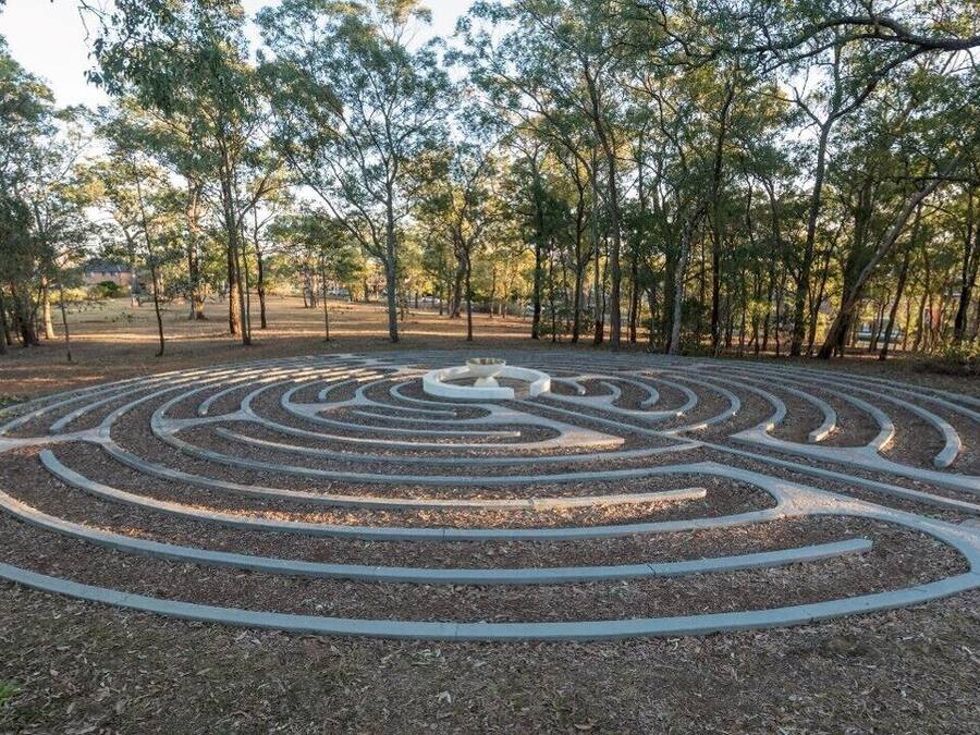 Um jardim labirinto com um caminho circular central rodeado por árvores.