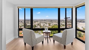 A room with two patterned chairs, a small table, and a large window offering a city view. - 3-bedroom house in charming La Mesa with AC (La Mesa)