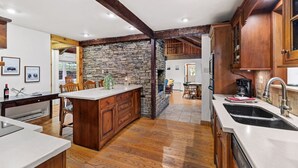 A kitchen with a central island, wooden cabinets, and a stone accent wall.