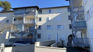 A multi-story residential building with balconies, a car parked in front, and a clear blue sky. - Capbreton – Clos Paisible residence in town centre with parking. (CAPBRETON)