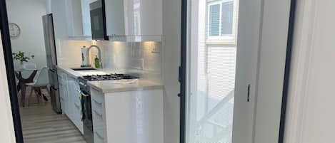 A modern kitchen with white cabinets, a gas stove, and a dining area with a table and chairs.