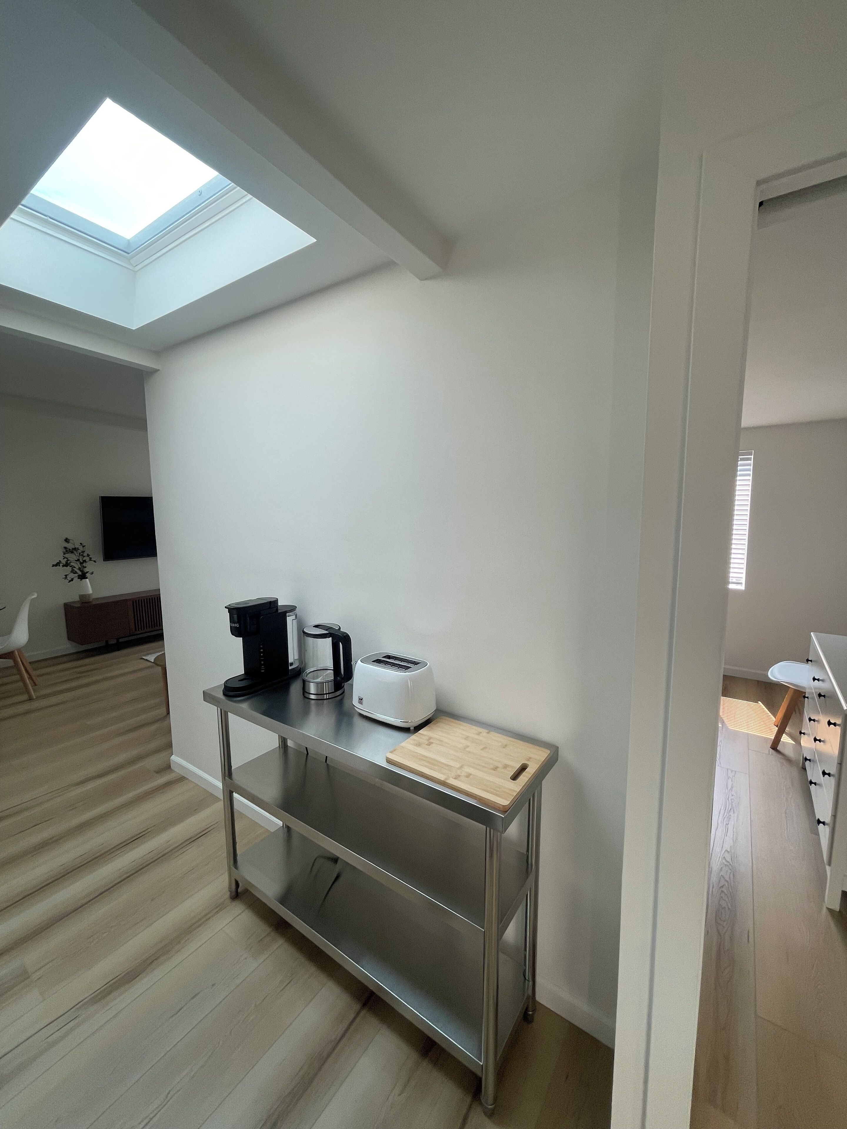 Una cocina moderna con tragaluz, una mesa de acero inoxidable, un tostador y una cafetera.