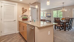 A modern kitchen with a granite countertop, wooden cabinets, and a built-in dishwasher.
