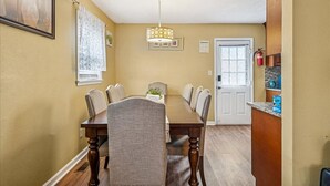 A dining room with a wooden table and chairs, a chandelier, and a door leading to another room. - Spacious Family Stay, Large Dining, 3 Cozy Bedrooms, Home Near Buckroe Beach (Hampton)