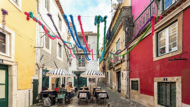 A narrow cobblestone street with outdoor seating and tables, decorated with colorful streamers. - Fado Soul Stay - Walk to Terreiro do Paço, bustling with fado (Lisboa)