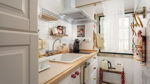 A kitchen with white cabinets, a double sink, and a wooden countertop. There is a black kettle and a coffee maker on the counter. - Fado Soul Stay - Walk to Terreiro do Paço, bustling with fado (Lisboa)