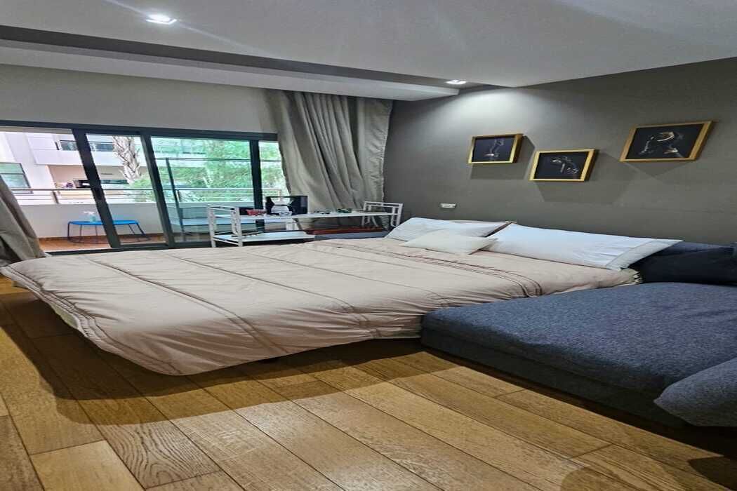 Een moderne slaapkamer met een groot bed, een klein bureau en een balkon met uitzicht.