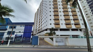 A multi-story building with balconies, a gated entrance, and a blue building adjacent to it. - Neri House - Ocean View, Beach Front (Cidade Ocian Praia Grande)