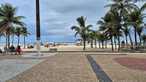 A beach with palm trees, a tiled walkway, and beachgoers. - Neri House - Ocean View, Beach Front (Cidade Ocian Praia Grande)