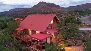 Una cabaña con techo rojo, una terraza con asientos exteriores y un jacuzzi.